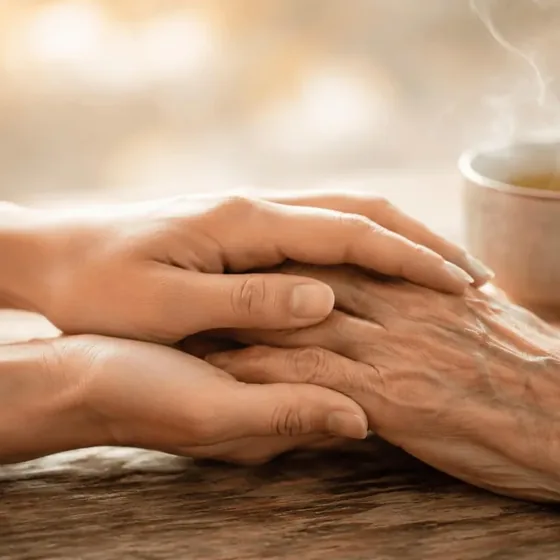 Aide à domicile à Figeac — mains bienveillantes tenant les mains d'une personne âgée